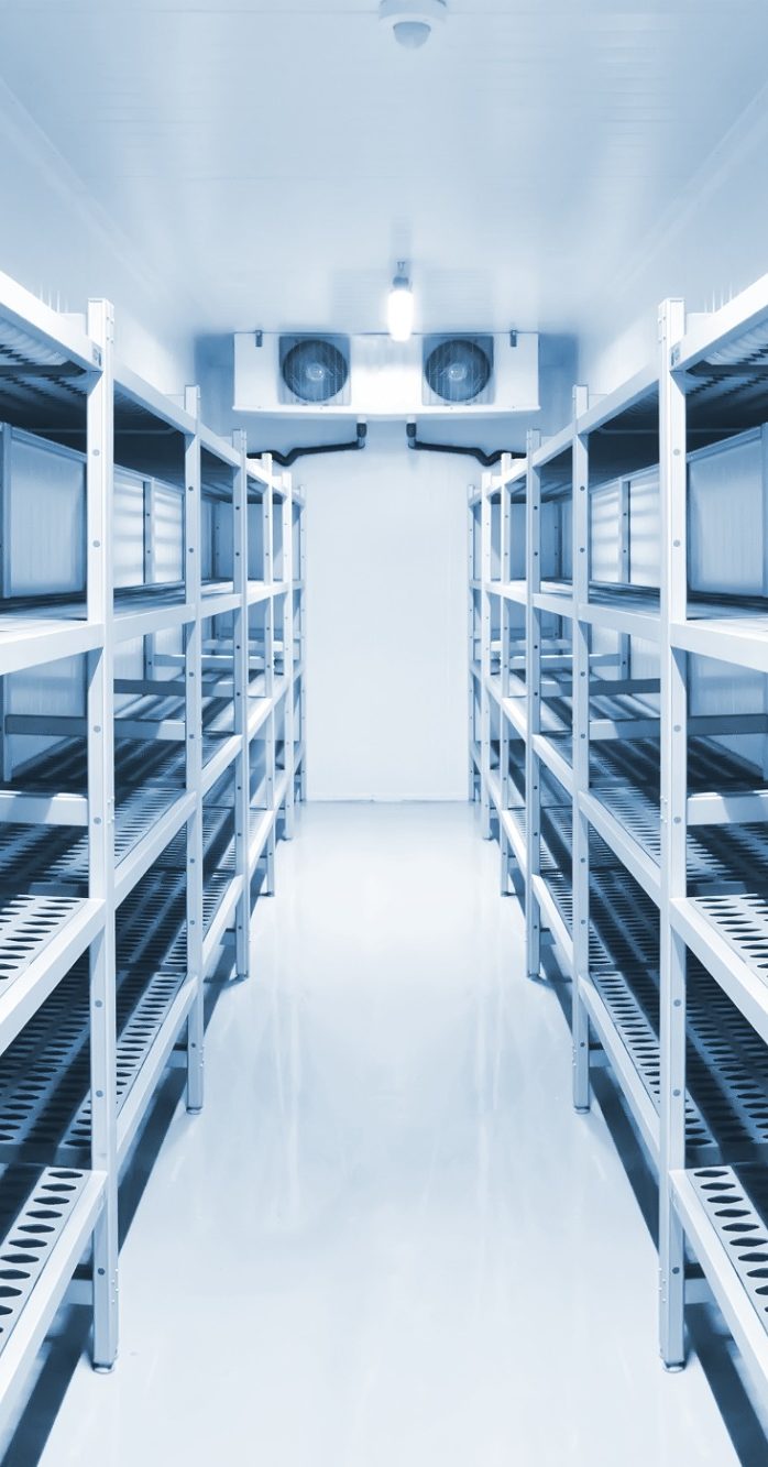 View of inside a larger mobile refrigeration unit which has racking to both sides and the condensing unit at the end